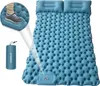 A blue inflatable camping mattress with two built-in pillows, shown with a close-up of a foot stepping on it and a rolled-up mattress in a carrying bag. Náhled obrázku produktu