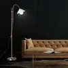 A floor lamp illuminates a luxurious living room with a tufted sofa and coffee table. Produktbild-Vorschau