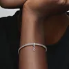 A close-up shot of a person's arm wearing a Pandora bracelet with a dangling charm. Náhled obrázku produktu