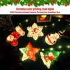 Christmas-themed decorative lights in various shapes like stockings, snowflakes, snowmen, stars, and trees, arranged on a dark background with some pinecones. Produktbild-Vorschau