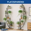 Two plant stands with plants are displayed in a living room setting next to a sofa and a dresser. Produktbild-Vorschau