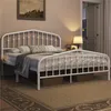 A white metal bed frame with a mattress and bedding in a bedroom setting. Produktbild-Vorschau