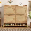 A wooden shoe cabinet with rattan doors and a metal frame, displaying shoes on the bottom shelf. Anteprima dell’immagine prodotto