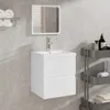 A white bathroom vanity with a sink and mirror, mounted on a tiled wall. Produktbild-Vorschau