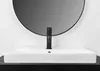 A close-up shot of a white rectangular sink with a black faucet, set against a white wall and a large round mirror. Podgląd zdjęcia produktu