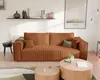 A modern living room with a corduroy sofa, coffee tables, and a framed picture on the wall. Produktbild-Vorschau