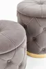 Close-up of two tufted ottomans with a gold base. Produktbild-Vorschau