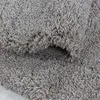 A close-up view of a shaggy, beige rug, showing its texture and a folded section. Produktbild-Vorschau