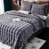 A close-up view of a dark gray plush blanket draped over a bed, with pillows in the background. Náhled obrázku produktu