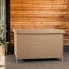 A beige woven storage box with a lid sits on a tiled patio in front of a wooden wall. Náhľad obrázku produktu