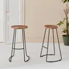 Two bar stools with wooden seats and black metal legs are shown in a room with a white door and a plant. Anteprima dell’immagine prodotto