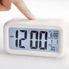 A finger presses the top button of a white digital alarm clock. Voir les images du produit