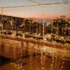 A beautifully decorated outdoor dining table set for an event, illuminated by numerous string lights. Náhled obrázku produktu