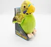A plush toy budgie in its packaging, presented against a white background. Produktbild-Vorschau