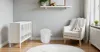 A nursery room with a white crib, a white armchair with a blanket, and a white diaper pail. Produktbild-Vorschau