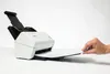 A hand is feeding a document into a white Brother ADS-4300N document scanner. Voir les images du produit