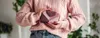 A person holding a small wallet in front of them, wearing a pink sweater and jeans. Podgląd zdjęcia produktu
