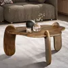 A wooden coffee table with decorative items on it, placed in a living room setting with a sofa in the background. Voir les images du produit
