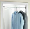 A telescopic tension rod mounted in a doorway, with a light blue dress shirt and a gray suit jacket hanging on it. Produktbild-Vorschau