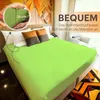A bed with a green fitted sheet and pillows, with a close-up inset showing the sheet's depth. Produktbild-Vorschau