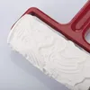 A close-up view of a white textured roller with a red handle. Produktbild-Vorschau
