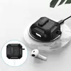 A black protective case for Apple AirPods is shown charging wirelessly on a marble-patterned charging pad. A single white AirPod is placed next to it. Voir les images du produit
