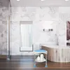 A modern bathroom with marble walls and a wooden bathtub, featuring a shower stool in the foreground. Produktbild-Vorschau