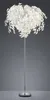 A floor lamp with a white, leaf-like shade and a silver pole and base, set against a plain gray background. Produktbild-Vorschau