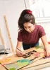 A young woman is drawing on a large piece of cardboard. Produktbild-Vorschau