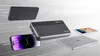 A collection of electronic devices including a power bank, smartphone, tablet, and laptop, arranged in a dynamic composition against a light gray and white background with abstract lines. Náhľad obrázku produktu