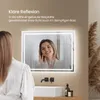 A woman is looking into a lighted mirror in a bathroom. The mirror has a fog-free feature. Podgląd zdjęcia produktu