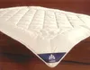 A white quilted blanket or duvet is laid out on a wooden surface. Produktbild-Vorschau