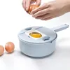 Hands cracking an egg over a light blue kitchen gadget with a white insert and a yellow egg yolk visible. Náhľad obrázku produktu
