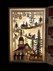 A lit-up wooden advent calendar depicting a winter village scene with Santa in a sleigh, reindeer, and children. Produktbild-Vorschau