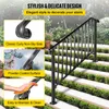 A black metal stair railing is installed on an outdoor staircase with green bushes and white steps. Produktbild-Vorschau