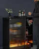 A man is pouring a drink from a decanter into a glass next to a bar cabinet. Produktbild-Vorschau
