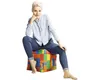 A woman is sitting on a cube-shaped ottoman with a brick pattern. The background is white. Produktbild-Vorschau