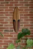 A wooden surfboard decoration mounted on a brick wall, with a monstera plant in the foreground. Produktbild-Vorschau