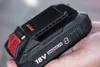 A hand holding a black and red power tool battery. Produktbild-Vorschau