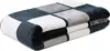 A folded blanket with a checkered pattern of dark gray, light gray, and white squares. Produktbild-Vorschau