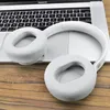 A pair of white headphones rests on a laptop keyboard, with the headphones partially covering the keys. The scene is set on a wooden surface. Voir les images du produit