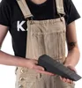 A person wearing overalls holds a black wedge-shaped tool. Voir les images du produit