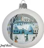 A white Christmas ornament with a painted winter village scene, including houses, a church, a snowman, and children playing. Náhled obrázku produktu