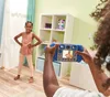 A child is taking a picture of another child with a toy camera in a bedroom. Podgląd zdjęcia produktu