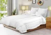 A white comforter is laid out on a bed in a bedroom setting. Produktbild-Vorschau