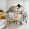 A woman is looking into a baby crib/playpen in a living room setting. Podgląd zdjęcia produktu