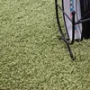 A close-up shot of a green shaggy carpet with a black magazine rack in the background. Podgląd zdjęcia produktu
