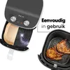 An air fryer with its basket shown, one side with paper liners and the other with cooked food. Text indicates ease of use. Produktbild-Vorschau