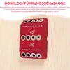 A red drilling jig with silver inserts is shown against a light wood background. Produktbild-Vorschau