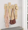 A wooden coat rack with a robe, a handbag, and a hat hanging on it, placed above a bench in a room. Náhled obrázku produktu